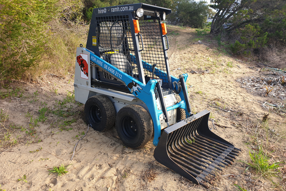 Skid steer fitted with rake bucket